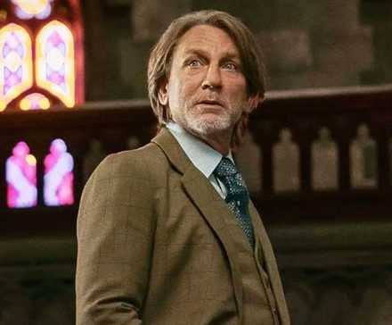 Daniel Craig as Benoit Blanc standing in a church in Wake Up Dead Man