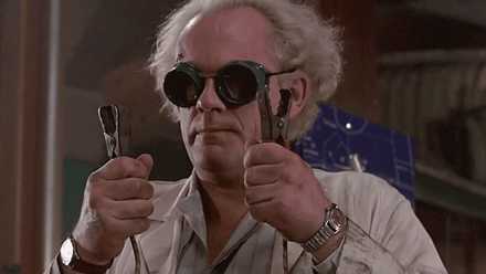 Christopher Lloyd holding two booster cables in Back to the Future