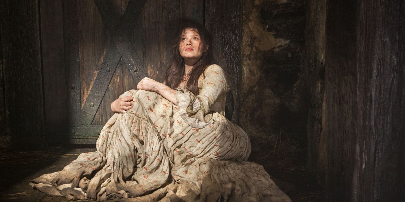 Dirty woman in a historical dress sitting on the floor
