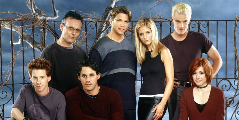 The cast of Buffy the Vampire Slayer looking at the camera with an iron fence behind.