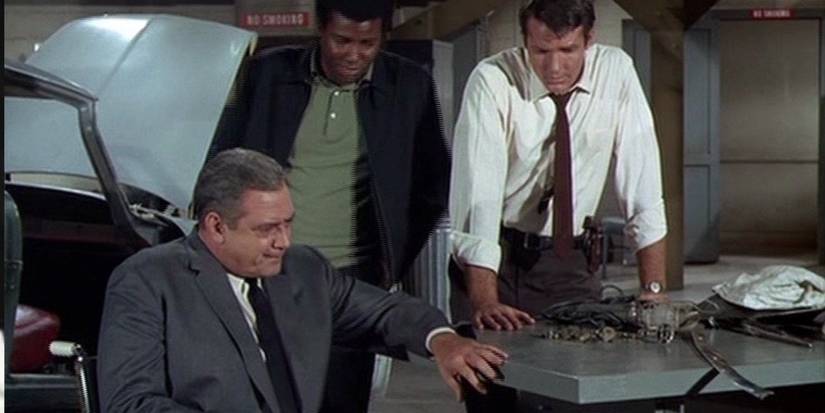 Chief Robert T. Ironside (Raymond Burr), Detective Sergeant Ed Brown (Don Galloway) and Officer Mark Sanger (Don Mitchell) look over evidence on a table in 1967's Ironside.