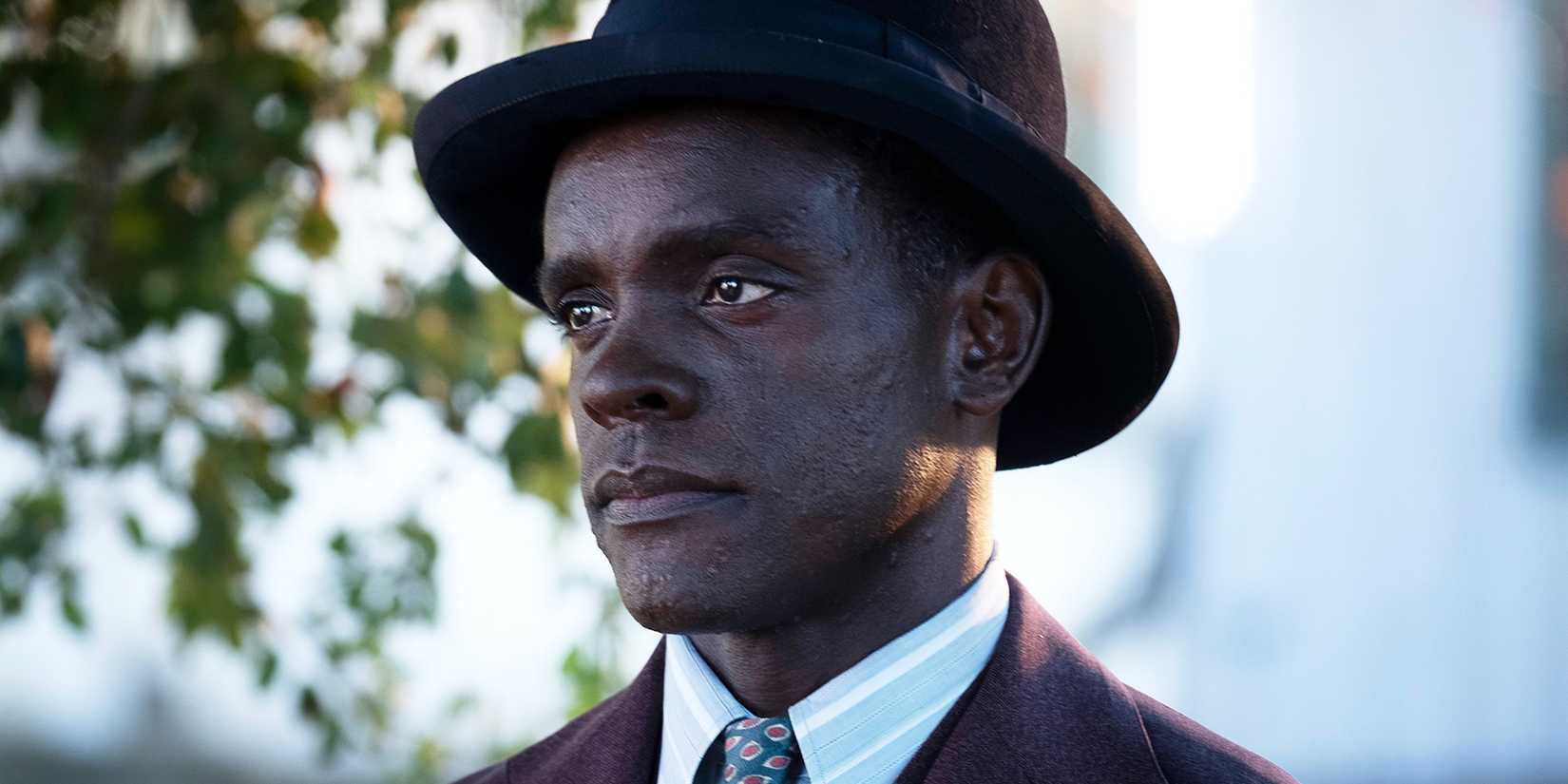 Chris Chalk wearing a hat and suit looking somberly ahead in When They See Us
