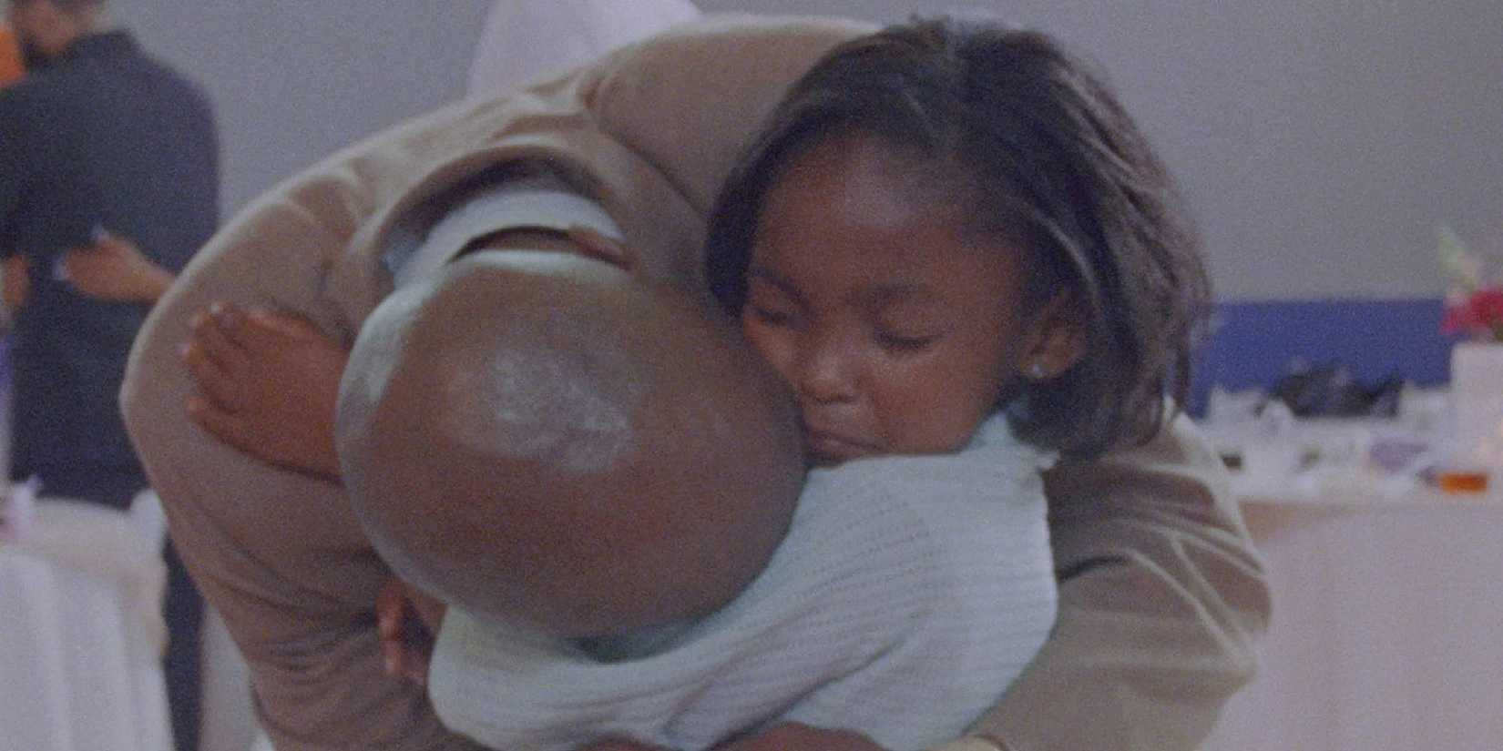 A dad and a child hug in Daughters