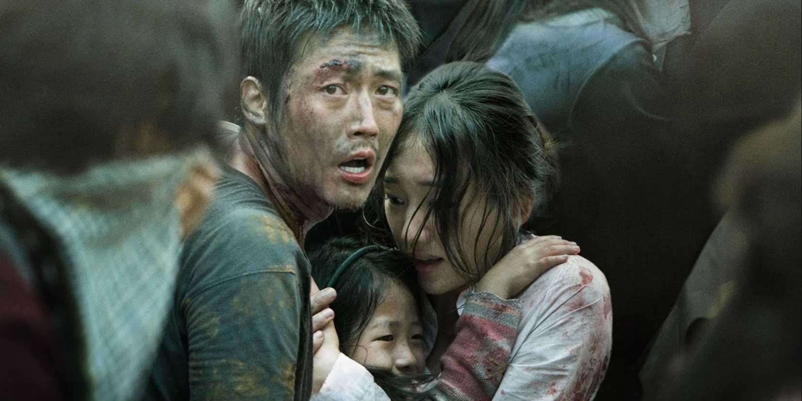 A man, woman, and young child huddle together in a crowd and look terrified in Flu aka Gamgi. 