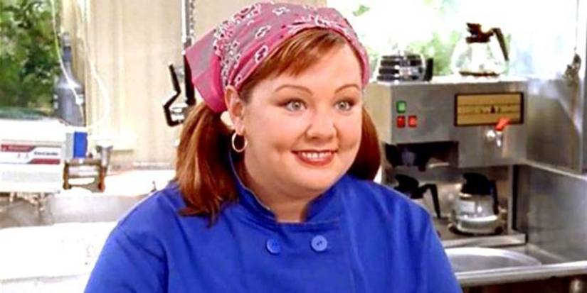 Melissa McCarthy as Sookie wearing a handkerchief on her hair and smiling in 'Gilmore Girls'.