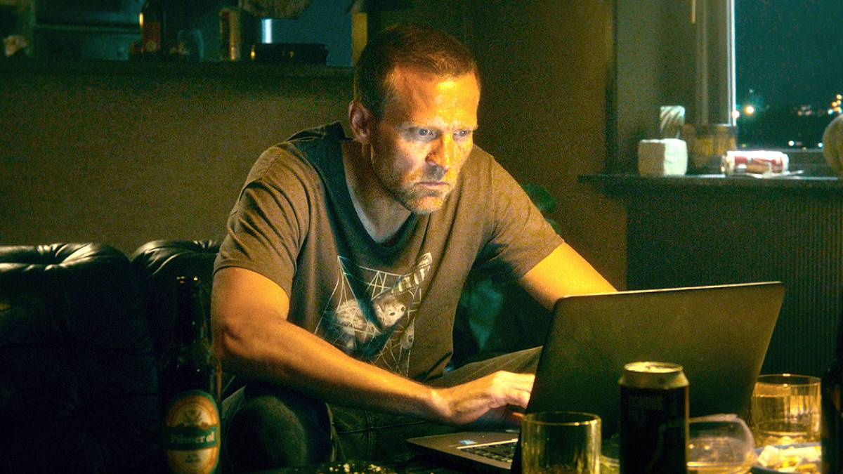 Tobias Santlemann leaning in and working on his laptop in Detective Hole