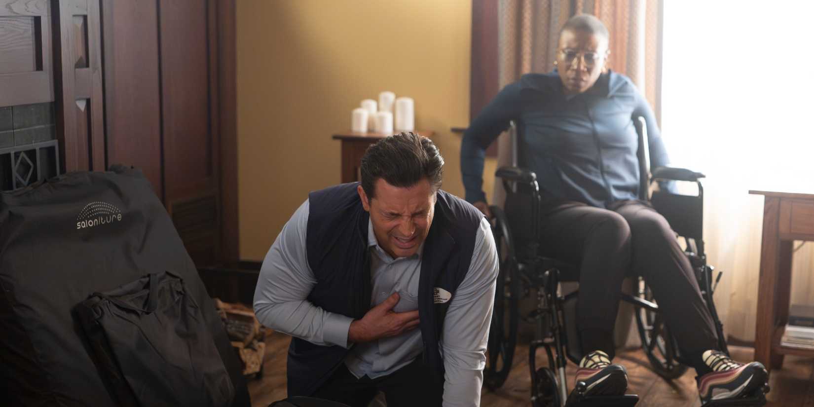 Hen watching from a wheelchair as her physical therapist, Adam, clutches his heart in pain, in 9-1-1 Season 9 Episode 9