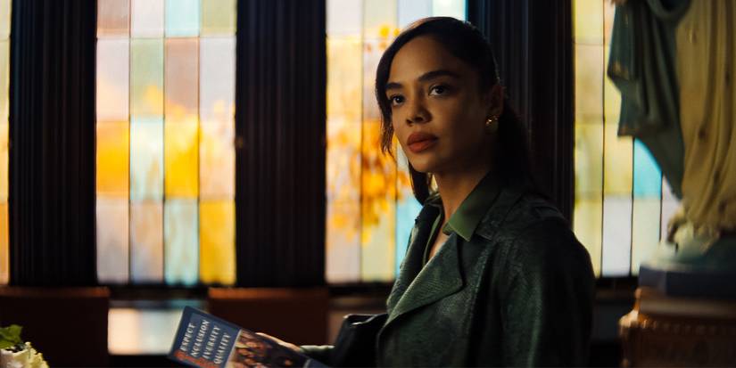 Tessa Thompson looking to the side with multicolored windows behind in His & Hers. 