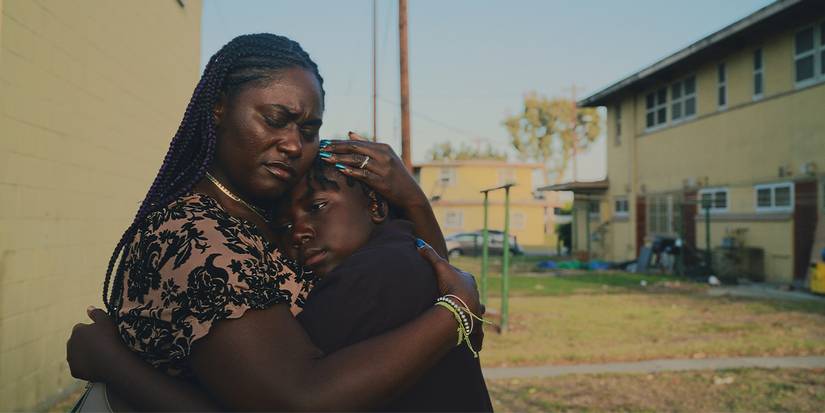 Seorang wanita memeluk seorang anak di luar gedung.