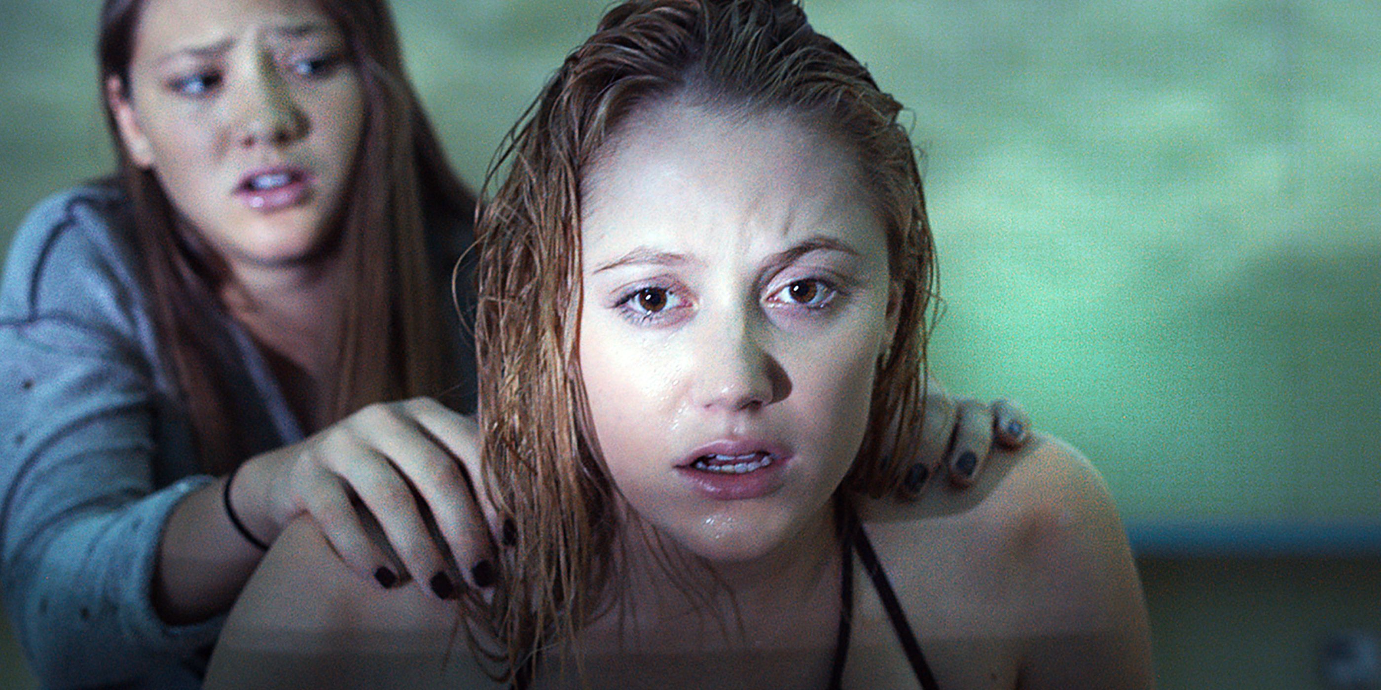 Jay looking in shock as another girl holds her by the shoulders in It Follows