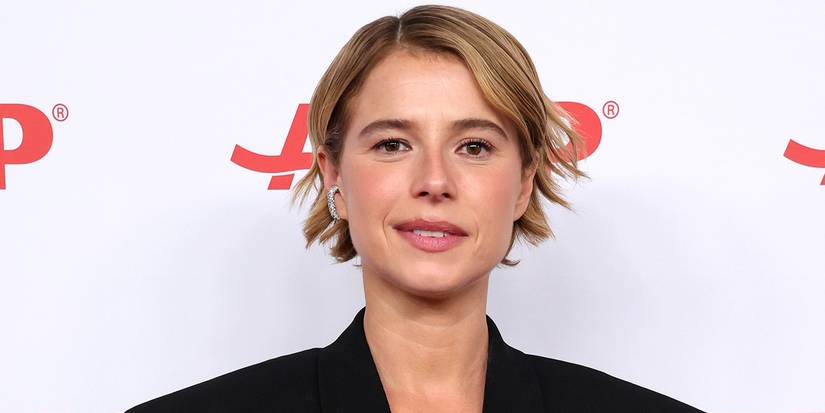 Jessie Buckley smiling at a red carpet.