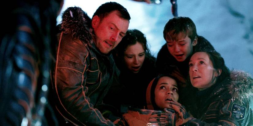 John (Toby Stephens), Maureen (Molly Parker), Will (Maxwell Jenkins), Penny (Mina Sundwall) and Judy Robinson (Taylor Russell) are huddled and looking up at someone in Netflix's Lost in Space.