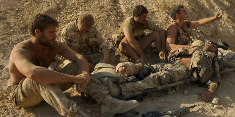 Four soldiers with a fifth one lying on the ground in Kajaki (Kilo Two Bravo)