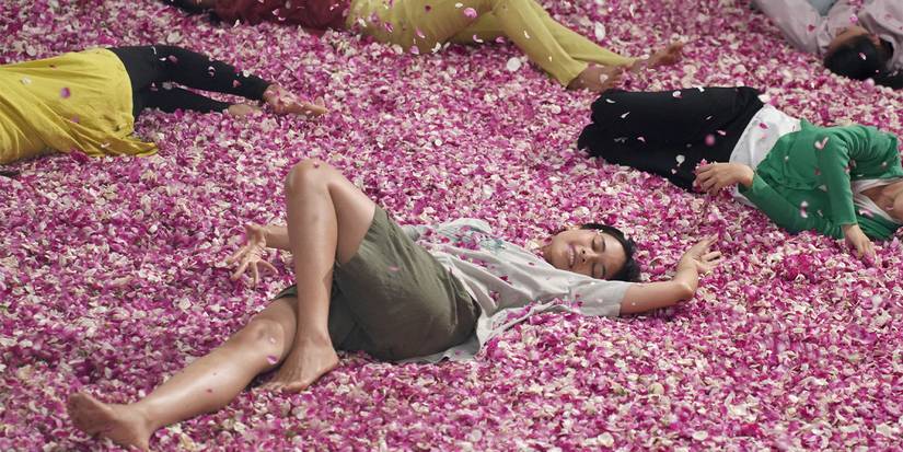 A group of people lying in a pile of pink flowers.