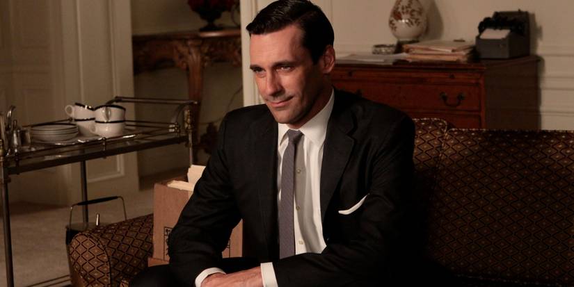 Jon Hamm as Don Drapper sitting and smiling in the 'Mad Men' episode "Shut the Door, Have a Seat."