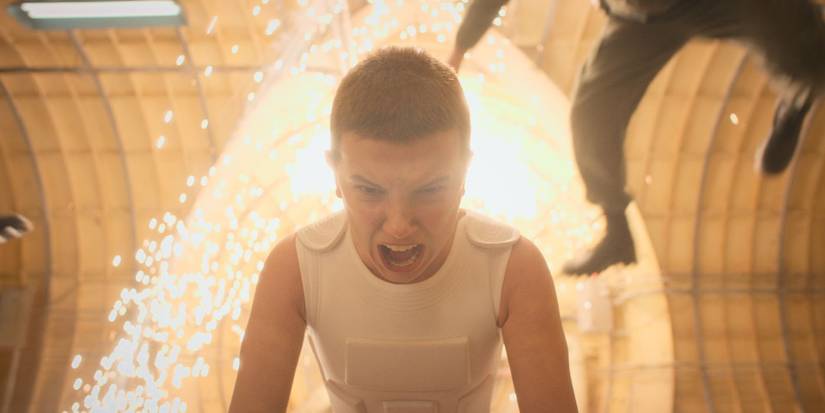 Eleven screaming with explosions behind in Stranger Things.