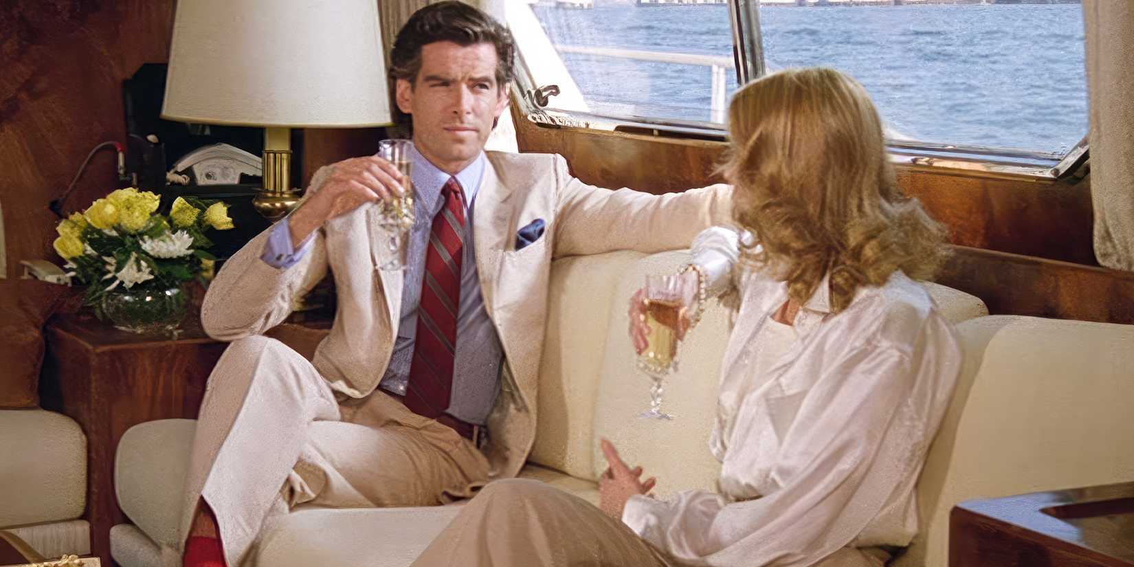 Pierce Brosnan's Ian holding a drink and sitting on a couch in Noble House
