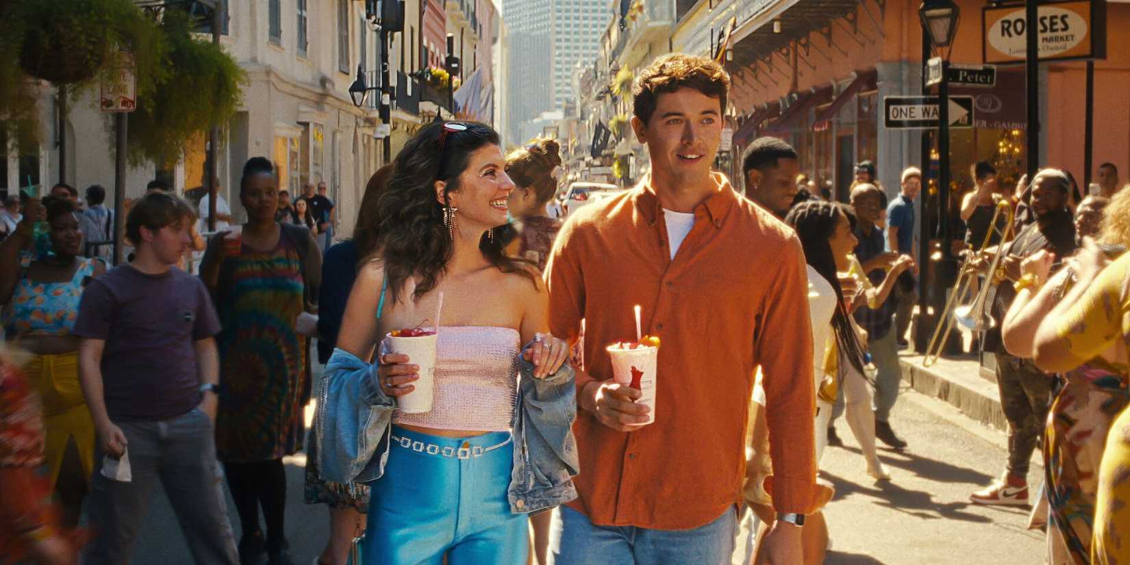 A man and woman walk down a street with pedestrians in People We Meet On Vacation. 