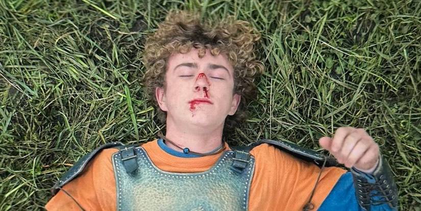 Walker Scobell as Percy lays in the grass with a bloody face after a fight on Season 2 of 'Percy Jackson and the Olympians.'