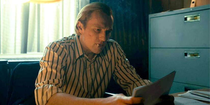 Artjom Gilz as Andrei sitting at a desk, looking at a document in Ponies.