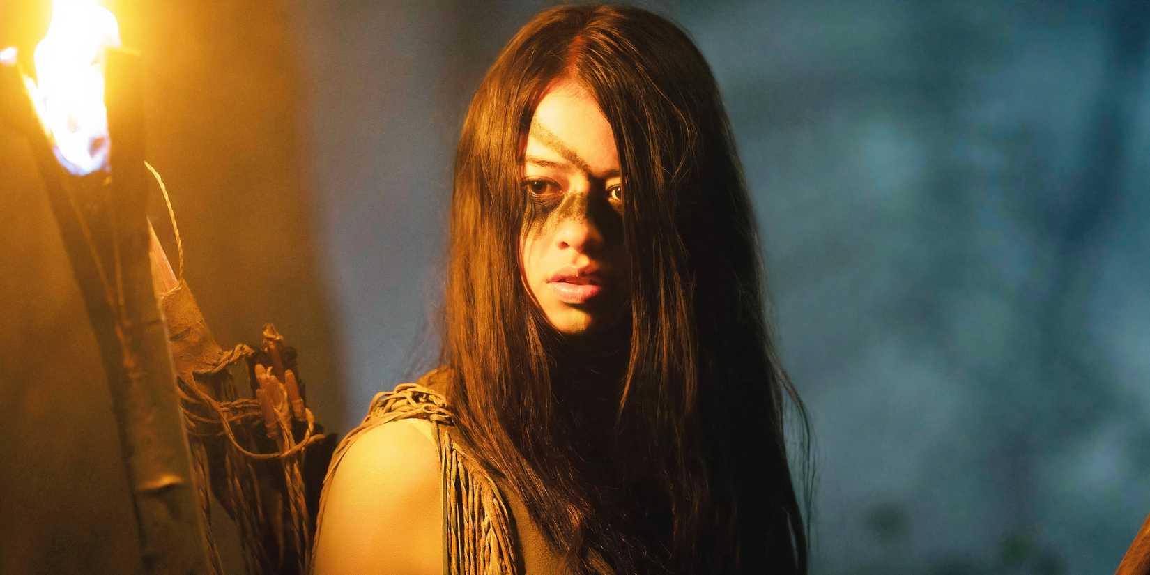 Amber Midthunder as Naru holding a torch in Prey.