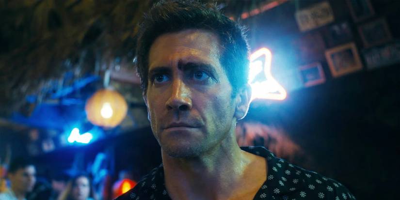 Jake Gyllenhaal lit up by neon lights in Road House