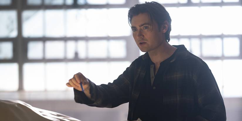 Xavier holding a small object out, frowning.