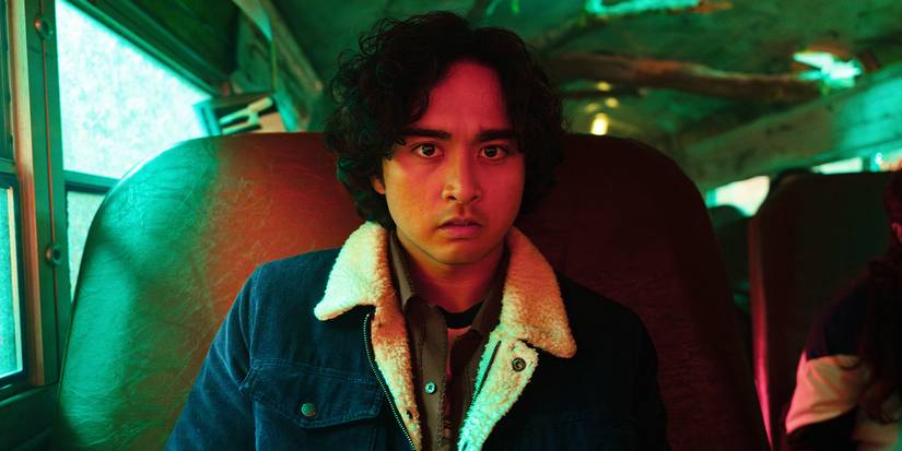 Simon sits on a bus, looking into the camera with a frightened expression.