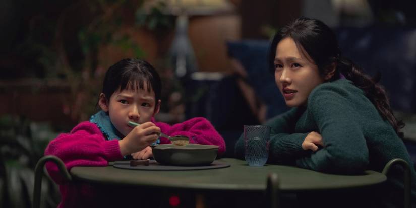 Son Ye-jin at a table with a kid looking slightly to the distance in 'No Other Choice'.