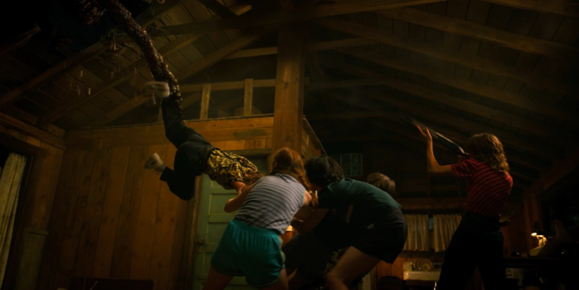 The cast hold onto someone as they are being pulled upward in Stranger Things.