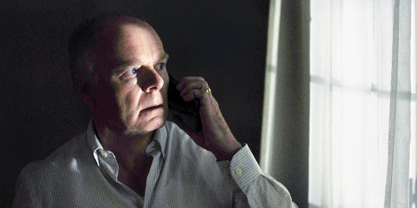 Huw talking on the phone and looking out a window with a frightened expression in The Game