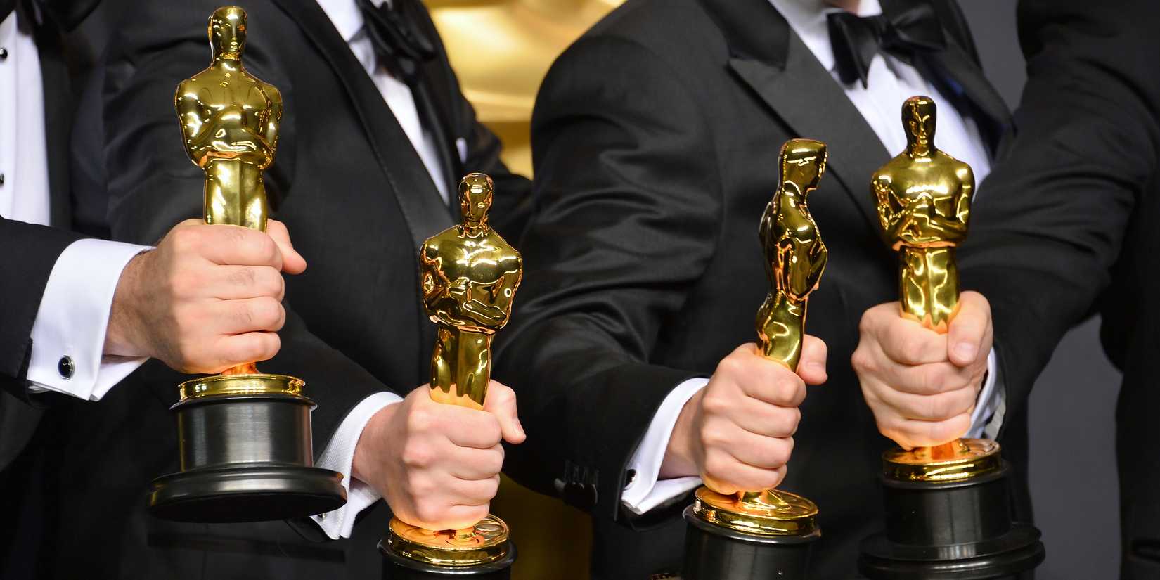 Four hands holding Oscar statues