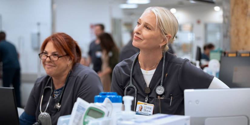 Dana Evans (Katherine LaNasa) smiles next to a colleague as they look in the same direction in 'The Pitt'.