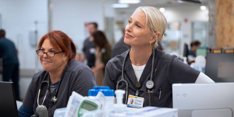 Dana Evans (Katherine LaNasa) smiles next to a colleague as they look in the same direction in 'The Pitt'.
