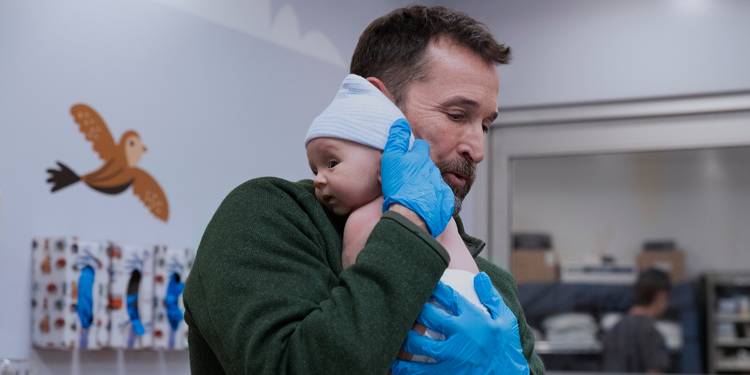 Noah Wyle holding a baby in The Pitt Season 2 Episode 1