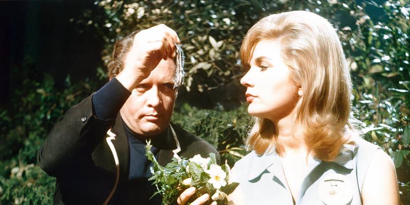 Номер Шесть сидит рядом с блондинкой, держащей цветы в «Узнике».