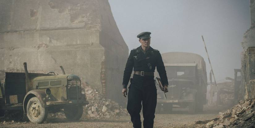David Schütter as Philip Gerkins walking through a destroyed town in The Tank