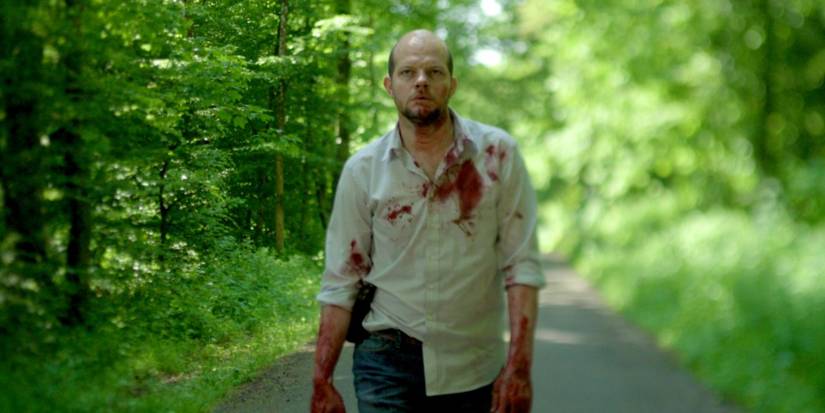 A cop walks along the road in a bloody shirt in 'The Break.' 