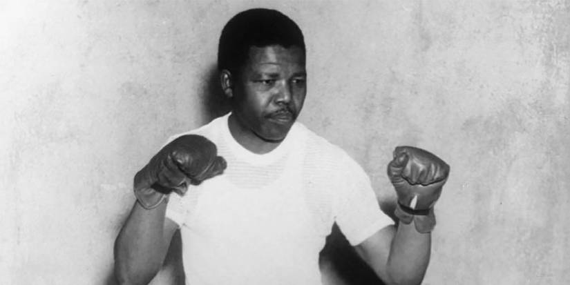 A black and white image of Nelson Mandela in a fighting stance with boxing gloves.
