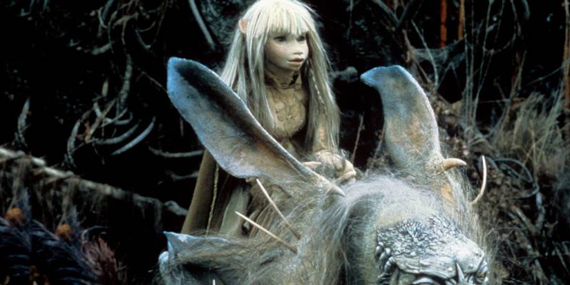 Girl with long pale hair rides a large, horned fantasy creature in a dark forest The Dark Crystal