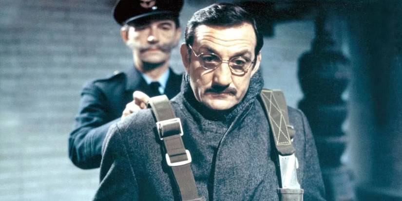 Man in glasses is restrained by a uniformed officer in a stark, tense setting in Army of Shadows