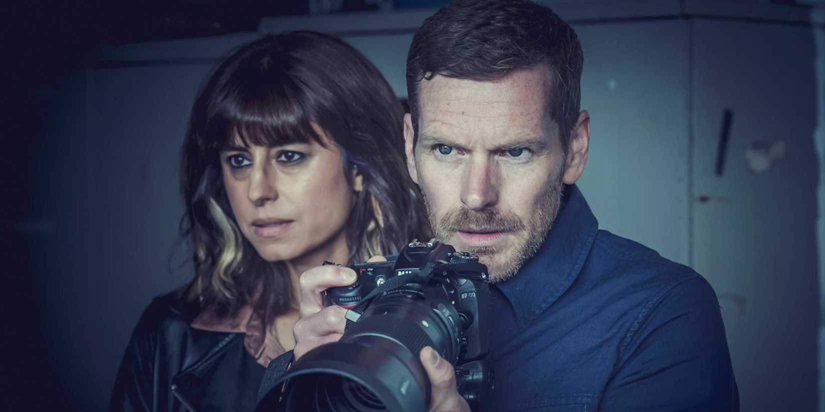 A man looks through a long lens camera next to a woman in 'Betrayal'