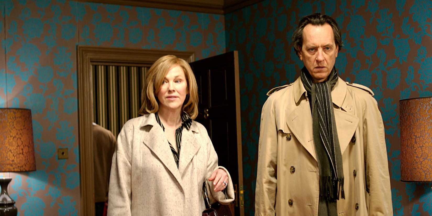 Catherine O'Hara as Jessica and Richard E. Grant as Franklin stand in a hotel room and look around in Penelope.