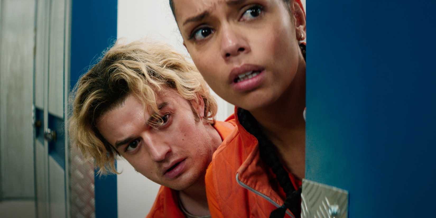 Georgina Campbell and Joe Keery peeking out of a corner in Cold Storage.