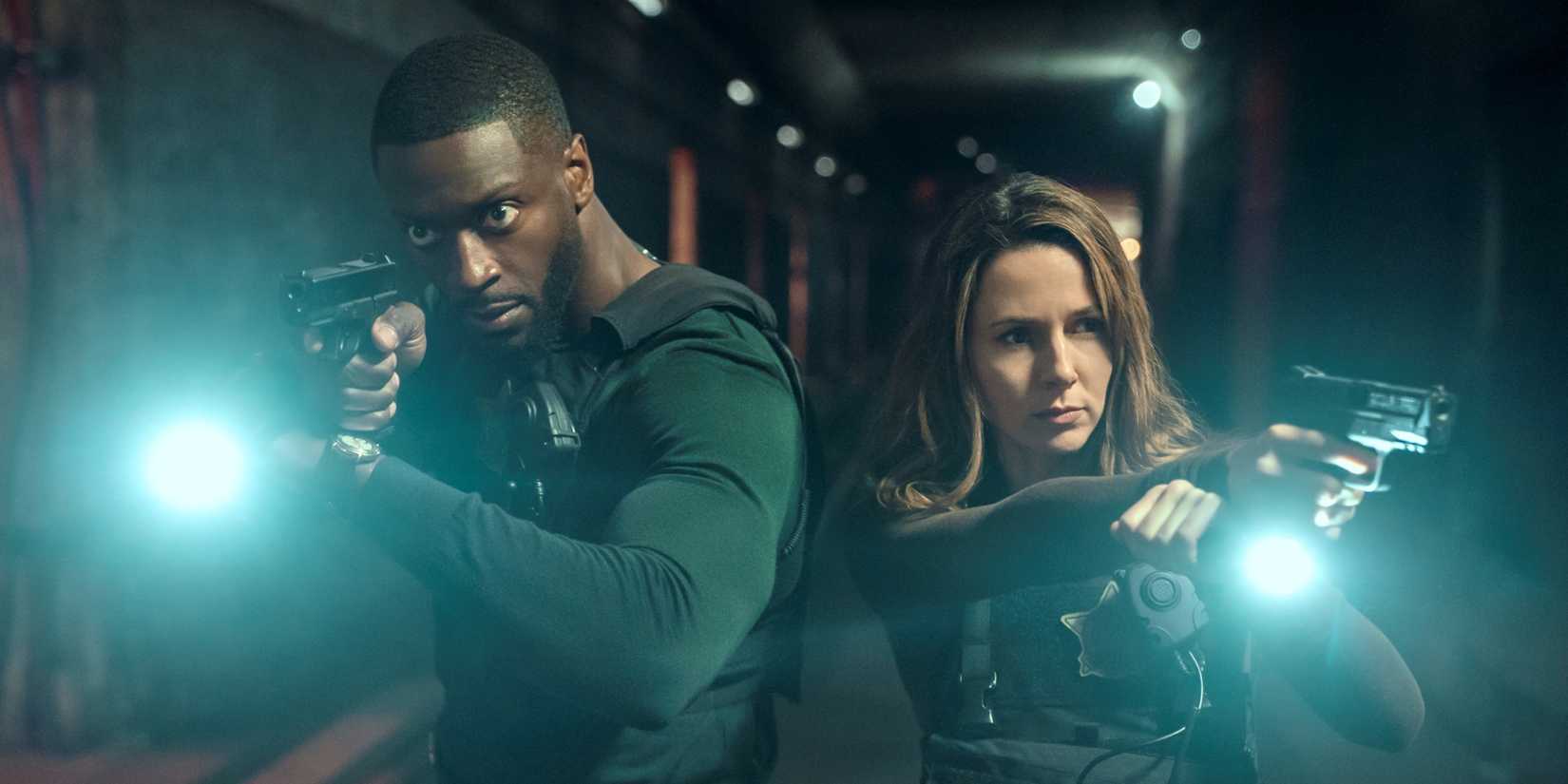 Aldis Hodge as Alex Cross and Alona Tal as Kayla Craig walking with flashlights and their guns out in Cross