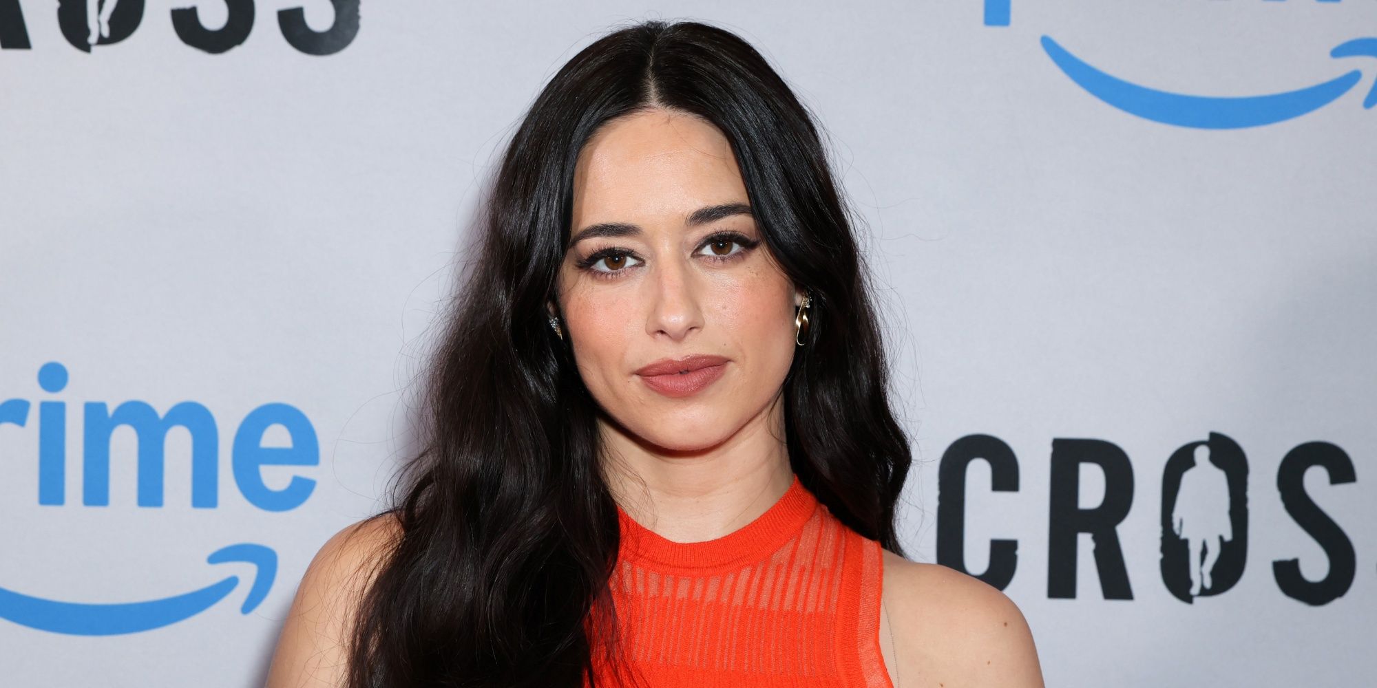 Jeanine Mason on the red carpet in a red sleeveless dress at the Los Angeles screening of Cross Season 2