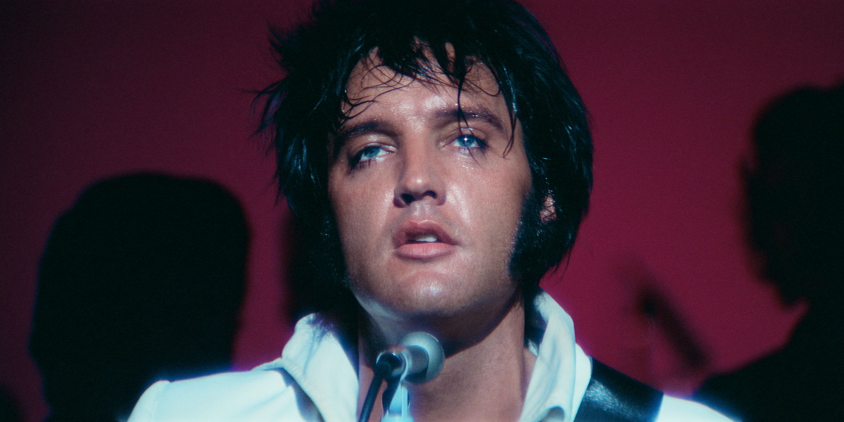 A close-up of Elvis Presley looking up while performing on stage.