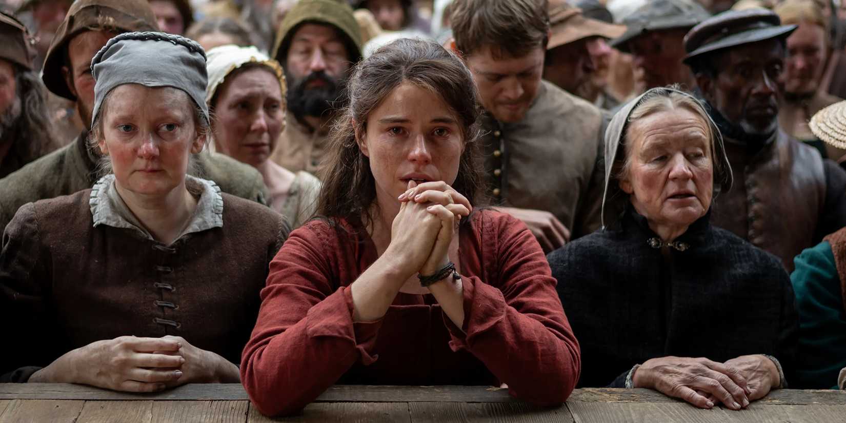 Jessie Buckley clasping her hands and leaning on the stage with the crowd in Hamnet