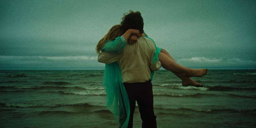 Ben Petrie as Homer carrying Grace Glowicki as Diane on the beach in Honey Bunch.