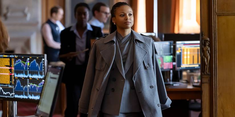 Myha'la as Harper walking in a grey coat and grey suit in Industry Season 4